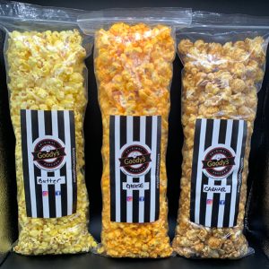 three bags of various gourmet flavored popcorn on a black table