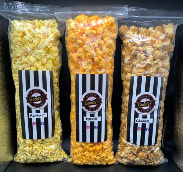 three bags of various gourmet flavored popcorn on a black table